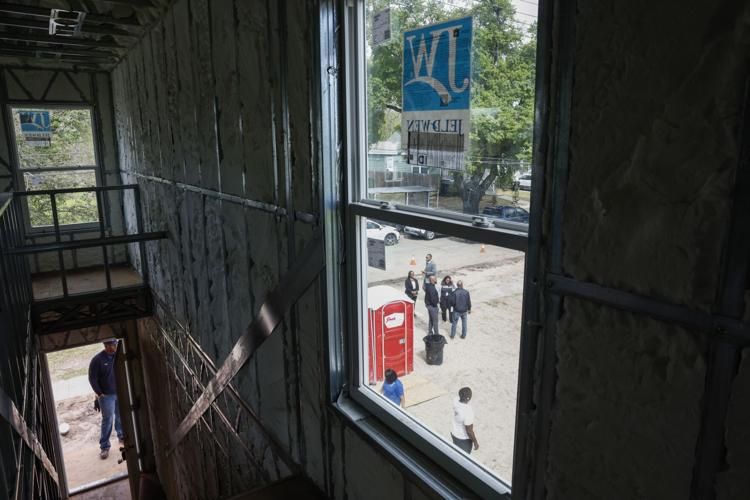 People are seen walking around through the window of a housing development under construction, with bare insulation